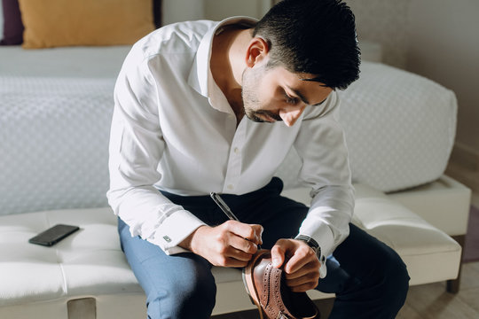 Hindu man writes something on his shoes sitting on white chouch