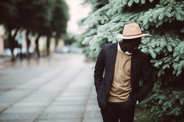 Handsome young Afro American man in casual wear and sun glasses walking outdoors in the street