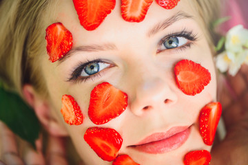 Beautiful woman with a strawberry mask, close-up, facial, natural cosmetics, lying on nature in a summer garden with jasmine in her hair