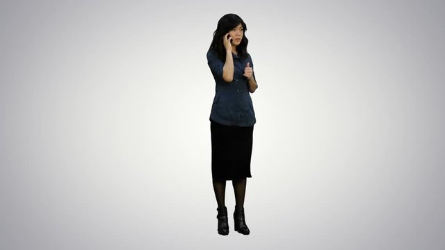 Angry asian business woman talking on cell phone on white background