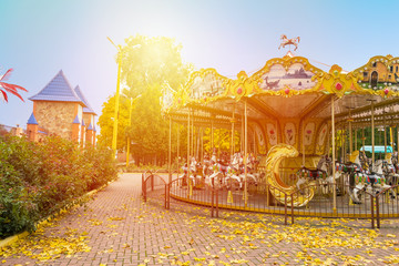 Merry-round-go Horse Carousel in Autumn park. Fall landscape with colorful carousel (roundabout),...