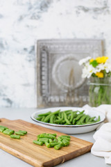 Freshly Picked Green Beans in a White Bowl, Some Cut on Cutting Board, all on Gray Background