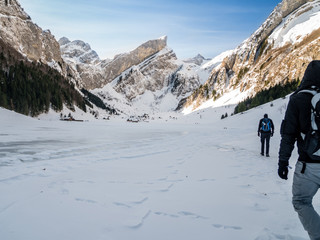 hiking over frozen lake with small village, swiss mountains