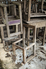 Fototapeta na wymiar Abandoned broken vintage wooden chairs and vintage wooden desks in old school