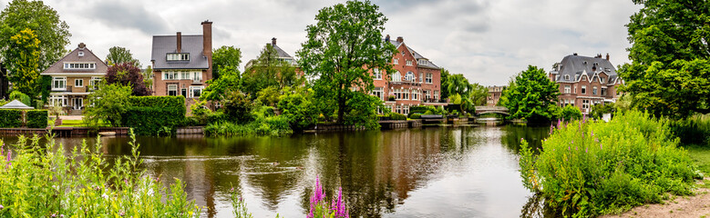 Fototapeta na wymiar old mansion with little bridge, amsterdam on a river panorama