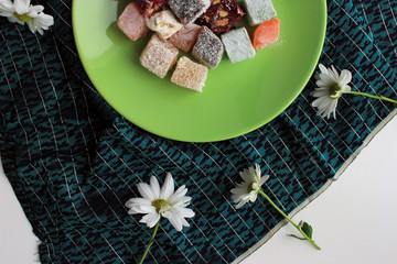 Sweets of turkish delights and fresh camomile on blue background