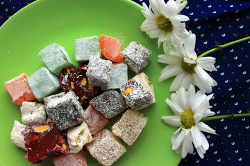 Sweets of turkish delights and fresh camomile on blue background