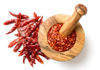 dried red pepper flakes in the wooden mortar, isolated on white, top view