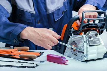 Professional technician working by repair service.Repairing chainsaw in repair shop.Small business.