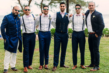 Handsome Indian groom and groomsmen in classy suits pose together on the lawn