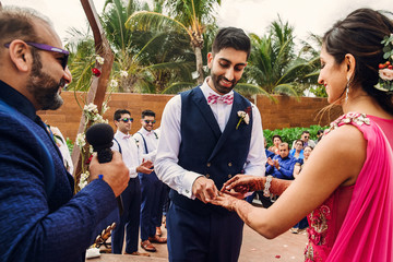 Indian groom puts wedding ring on bride's hand with henna tattoos