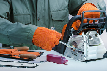 Professional technician working by repair service.Repairing chainsaw in repair shop.Small business.