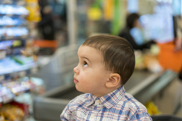 The little boy on a background of cash in a supermarket