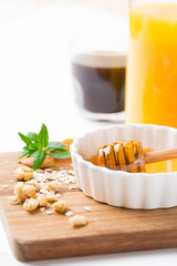 Healthy breakfast in glass mason jar with oat flakes, granola, milk, dry fruits and nuts, dates, honey, orange juice, eggs for morning fitness on wooden board platter on white background isolated