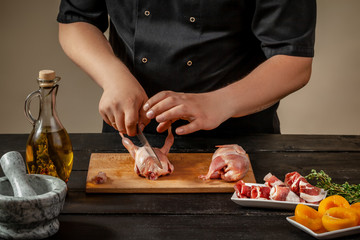 The chef prepares raw quail carcasses in the kitchen. Fresh raw meat quails ready for cooking on the wooden board