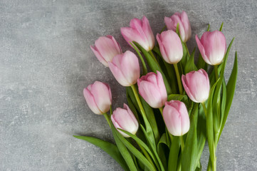 Bouquet of pink flowers on gray textured ackground. Holiday card. Copy space, top view. Spring concept.