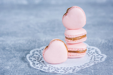 Pink strawberry macarons on blue texture background. Heart shaped. French delicate dessert. Copy space, selective focus. Spring concept.