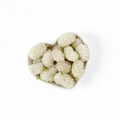 Fresh white organic mulberries in a heart bowl with copy space.