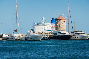 Windmills, boats, yachts and cruise ship in Mandraki harbor in City of Rhodes (Rhodes, Greece)