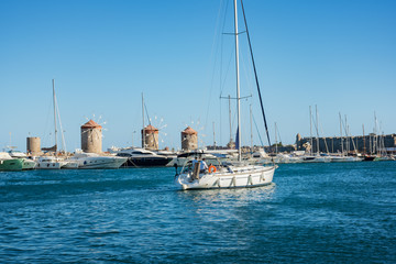 Fototapeta premium Boats, yachts and windmills in Mandraki harbor in City of Rhodes (Rhodes, Greece)
