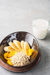 Oats Barley Wheat Rye Corn mix flake proper nutrition diet with pieces banana orange and glass of milk