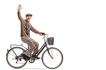 Naklejka premium Cheerful senior riding a bicycle and waving at the camera