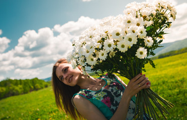 Beautiful young girl with a huge bouquet of daisies on a boundless field happy. Beautiful advertising background