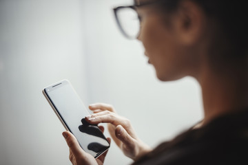 Young brunette girl with glasses holding mobile phone