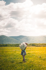 Beautiful young girl with a huge bouquet of daisies on a boundless field happy. Beautiful advertising background