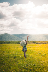 Beautiful young girl with a huge bouquet of daisies on a boundless field happy. Beautiful advertising background