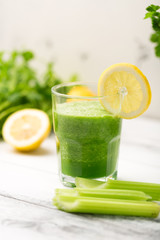 Green cocktail smoothie parsley celery lemon lime slices, healthy drink ingredients, glass of beverage on white wooden table, detox diet clean eating, with vegetables on table