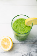 Green cocktail smoothie parsley celery lemon lime slices, healthy drink ingredients, glass of beverage on white wooden table, detox diet clean eating, with vegetables on table