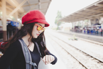 Charming beautiful woman is looking at her wristwatch. Gorgeous woman gets worried because a train gets so late. Attractive traveler women has to go to destination in time. She feel upset. copy space