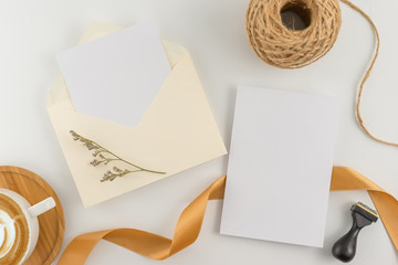 A wedding concept. Wedding Invitation, envelopes, cards Papers on white background with ribbon and decoration. Top view, flat lay, copy space
