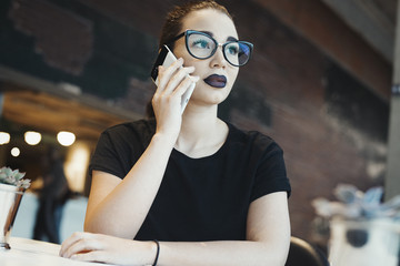 Young brunette girl with glasses talking by mobile phone