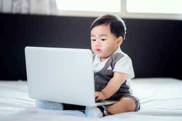 Asian baby sit in working action with business uniform and note book computer, this immage can use for education, family, kid, child, and business concept