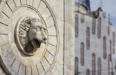 old concrete and stone sculpted feature of a lions head gazing out with fierce eyes