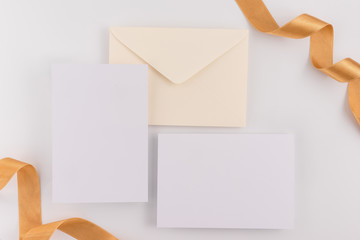 Fototapeta premium A wedding concept. Wedding Invitation, envelopes, cards Papers on white background with ribbon and decoration. Top view, flat lay, copy space