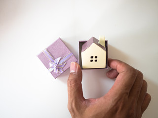 Hand is putting Small House model in gift box