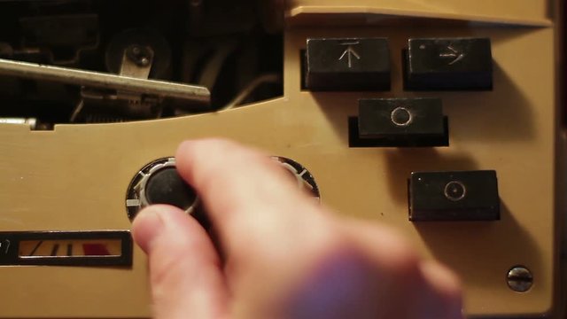 Male hand push play/stop button on vintage classic tape reel audio recorder.