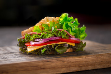 Tasty breakfast sandwich with lettuce, ham, cheese and tomato.