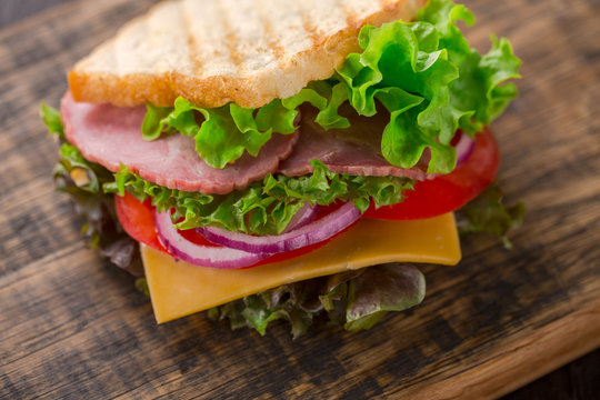 Tasty breakfast sandwich with lettuce, ham, cheese and tomato.
