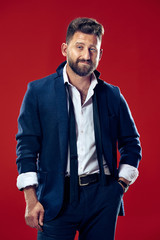 Obraz premium The happy business man standing and smiling against red background.