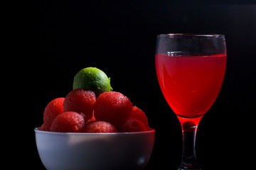 Salad of red and yellow balls of watermelon, photo black style,red fruit juice
