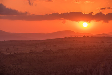 A red pink sunset, with the sun a low white ball beneath purple clouds at Blyde River Canyon in Mpumalanga, South Africa