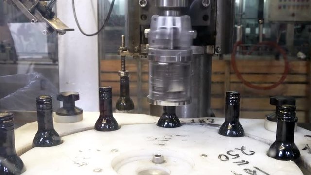 Spinning caps on bottles of red wine using professional modern equipment