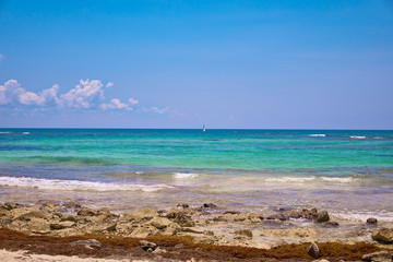 View of tropical beach. Tourists ride parasailing boat with parachute. Sailing yacht sails on waves. Turquoise water of the Caribbean Sea. Riviera Maya Mexico.