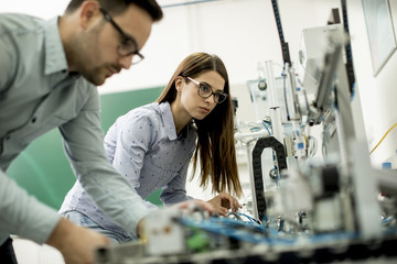 Young couple of students working at robotics lab