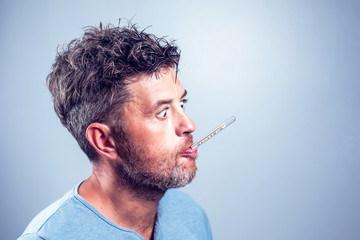 Sick man with thermometer in mouth,looking and worry at thermometer on white background,healthcare...