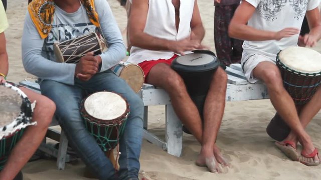 Unidentified man playing on drum at the beach. 